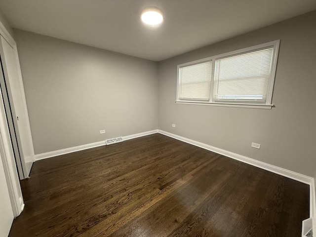 unfurnished bedroom with baseboards, visible vents, and dark wood-style flooring