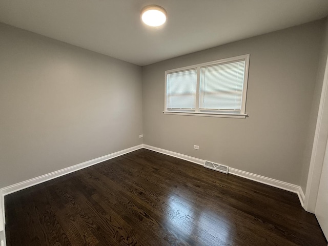 spare room with visible vents, dark wood-type flooring, and baseboards