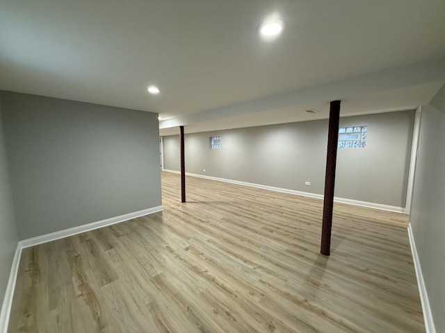 finished below grade area with recessed lighting, visible vents, baseboards, and light wood-style floors