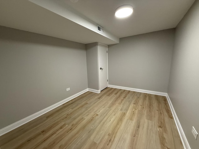 finished basement featuring baseboards, visible vents, and light wood-type flooring