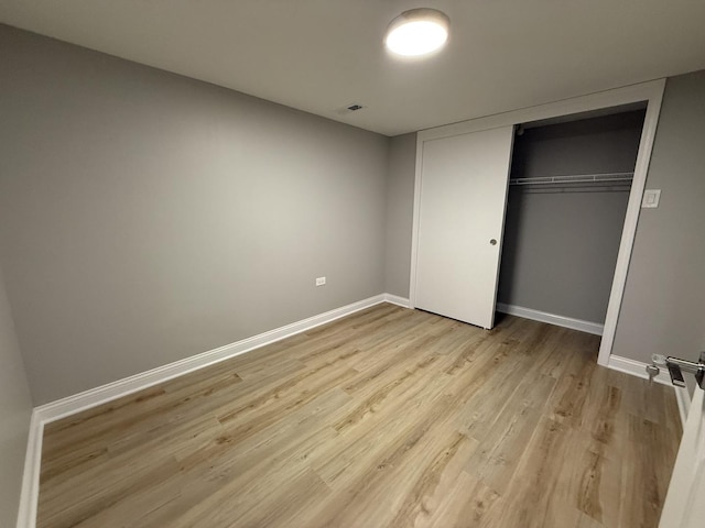 unfurnished bedroom with a closet, baseboards, and light wood-style floors