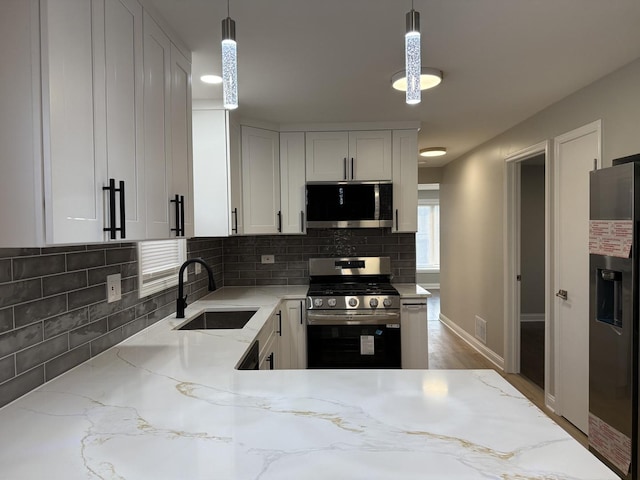 kitchen with tasteful backsplash, decorative light fixtures, light stone counters, stainless steel appliances, and a sink