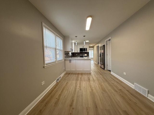 kitchen featuring visible vents, white cabinetry, stainless steel appliances, a peninsula, and baseboards