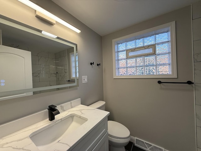 bathroom with visible vents, baseboards, toilet, vanity, and a shower