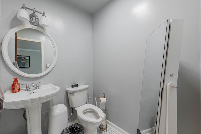 half bath featuring a sink, baseboards, and toilet