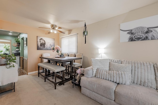 living area featuring a ceiling fan, light colored carpet, and baseboards