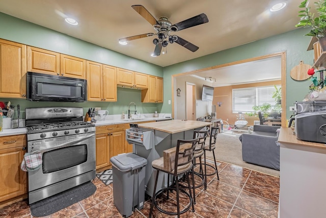 kitchen with ceiling fan, a sink, light countertops, black microwave, and gas range