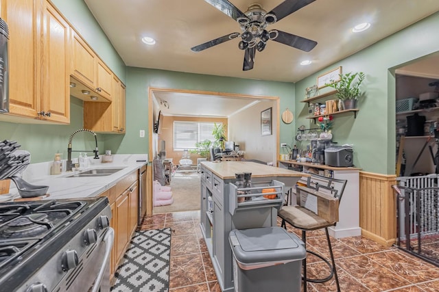 kitchen with gas stove, a ceiling fan, a wainscoted wall, recessed lighting, and a sink