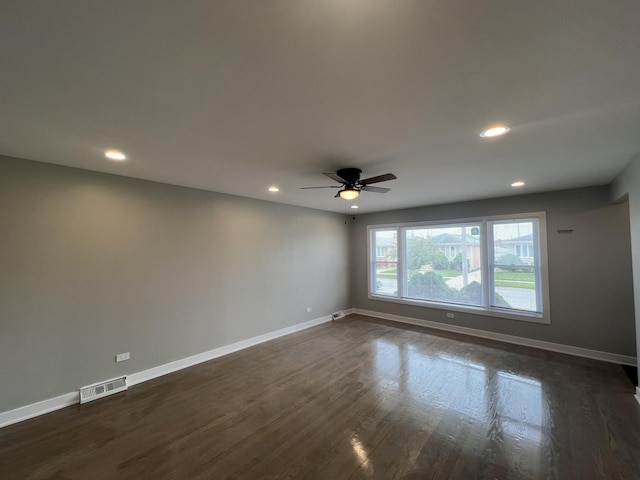 unfurnished room with dark wood-style floors, visible vents, and baseboards