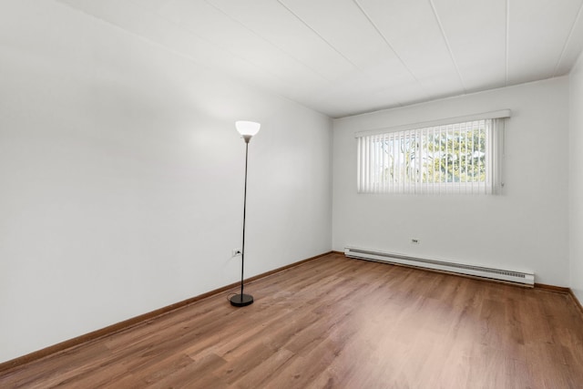 unfurnished room with wood finished floors, baseboards, and baseboard heating