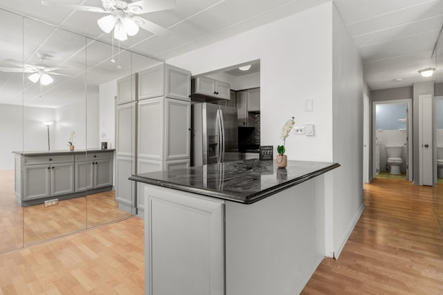 kitchen with a ceiling fan, a peninsula, stainless steel fridge with ice dispenser, and gray cabinetry