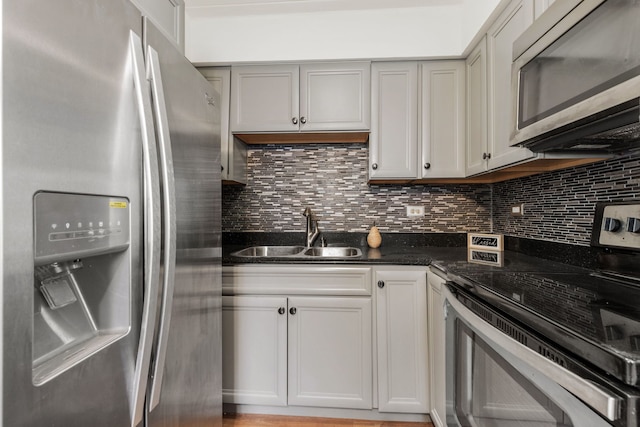 kitchen with a sink, stainless steel appliances, dark stone countertops, and decorative backsplash