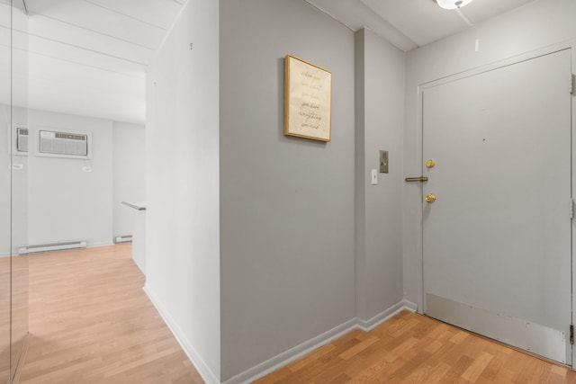 interior space featuring light wood-type flooring, a baseboard heating unit, baseboards, and an AC wall unit