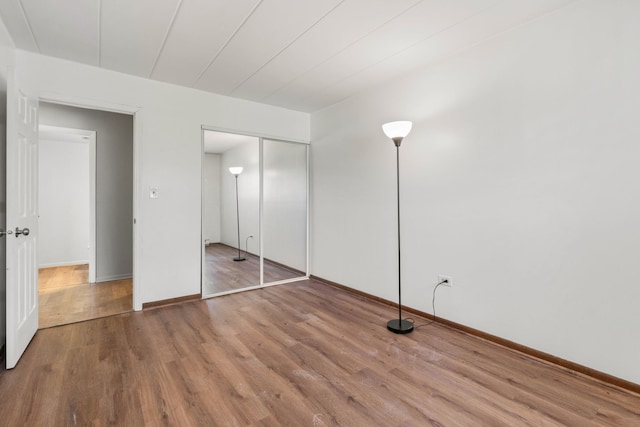 unfurnished bedroom with a closet, baseboards, and wood finished floors