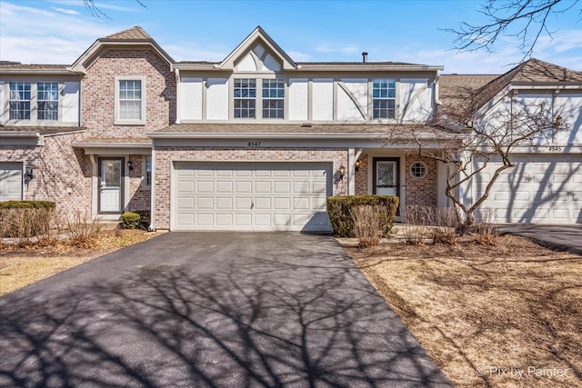 view of front facade featuring brick siding, stucco siding, driveway, and a garage