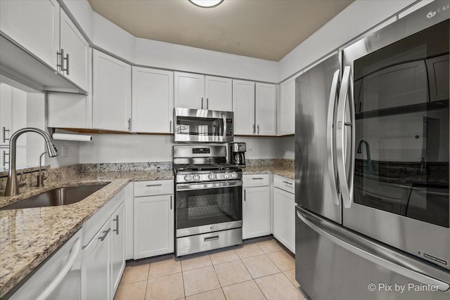 kitchen with light tile patterned floors, white cabinets, appliances with stainless steel finishes, and a sink