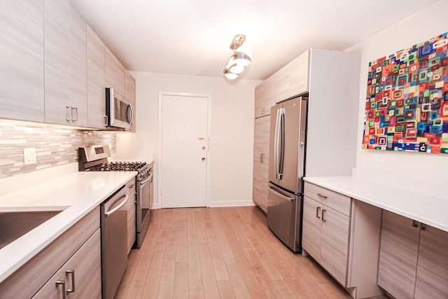 kitchen featuring decorative backsplash, light countertops, light wood-style floors, appliances with stainless steel finishes, and modern cabinets