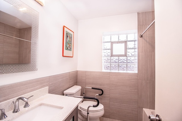 full bathroom featuring a wainscoted wall, toilet, tile walls, and vanity