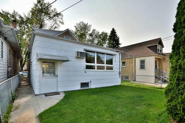 rear view of house featuring a lawn and fence