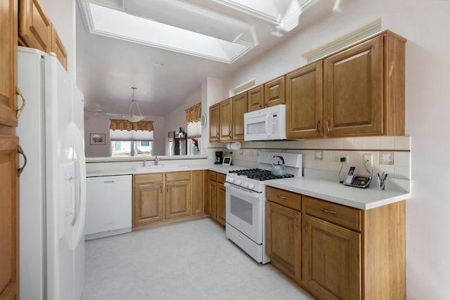 kitchen featuring light floors, light countertops, decorative backsplash, white appliances, and a sink