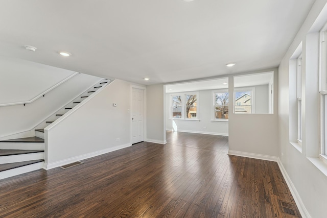 unfurnished living room with visible vents, stairway, baseboards, and dark wood-style flooring