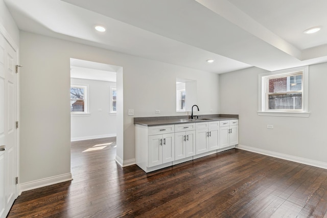 kitchen with dark wood-type flooring, recessed lighting, baseboards, and a sink