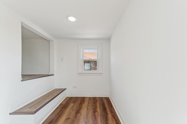 hallway with baseboards and dark wood-style flooring