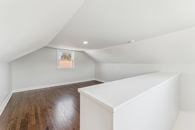 bonus room with dark wood finished floors, lofted ceiling, and baseboards