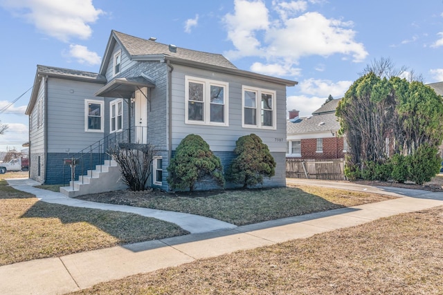 bungalow-style house featuring a front yard, fence, and roof with shingles