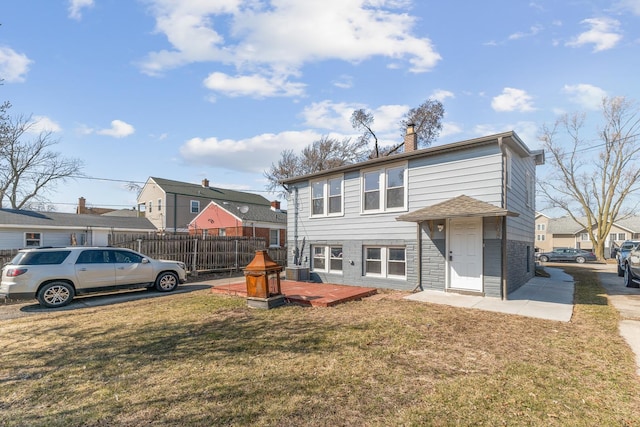 rear view of house with fence, a lawn, a residential view, and a chimney