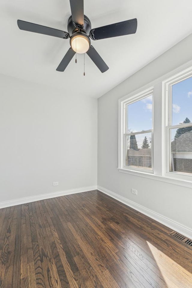 unfurnished room featuring baseboards, visible vents, dark wood-style flooring, and ceiling fan