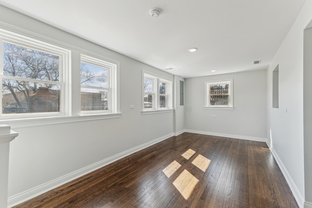 unfurnished room with visible vents, dark wood-style floors, and baseboards