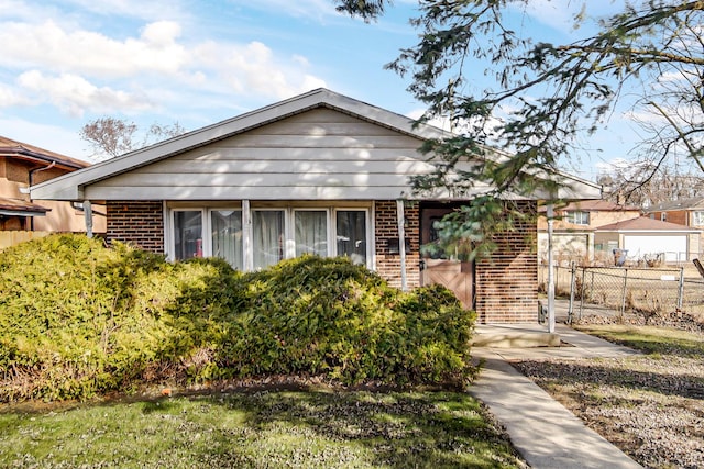 bungalow-style house featuring fence and brick siding