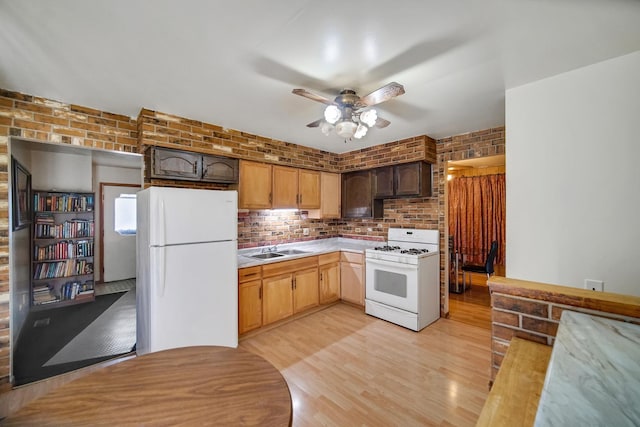 kitchen with brick wall, light countertops, white appliances, a ceiling fan, and a sink