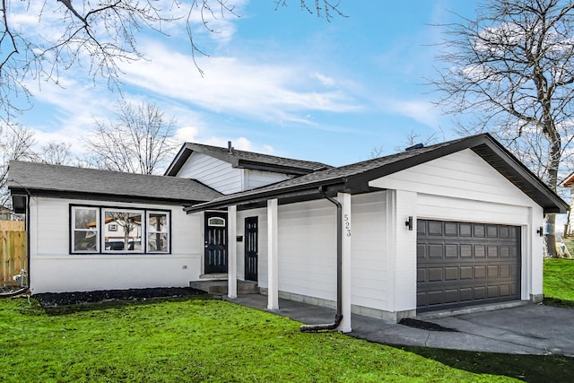 split level home with an attached garage, a shingled roof, a front yard, and fence