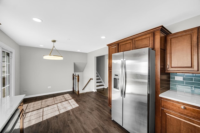 kitchen featuring dark wood-style floors, stainless steel fridge, brown cabinetry, light countertops, and decorative backsplash