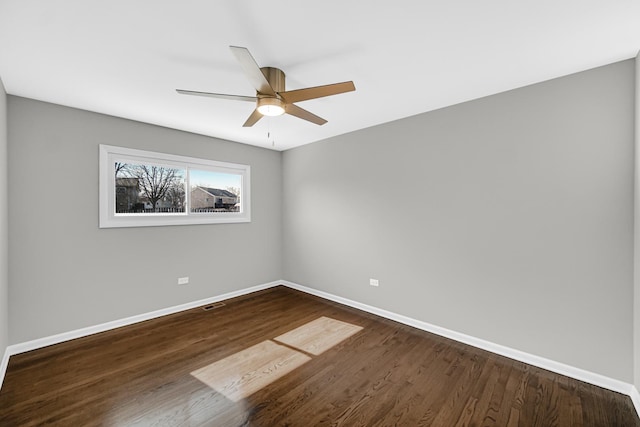 empty room featuring dark wood finished floors, visible vents, baseboards, and ceiling fan