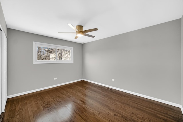 spare room with visible vents, dark wood-style floors, baseboards, and ceiling fan