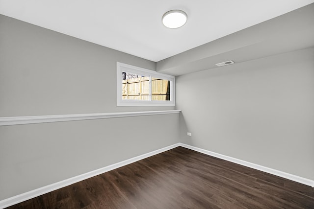 unfurnished room with visible vents, baseboards, and dark wood-style floors