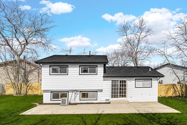 rear view of property with a patio, cooling unit, fence, roof with shingles, and a lawn