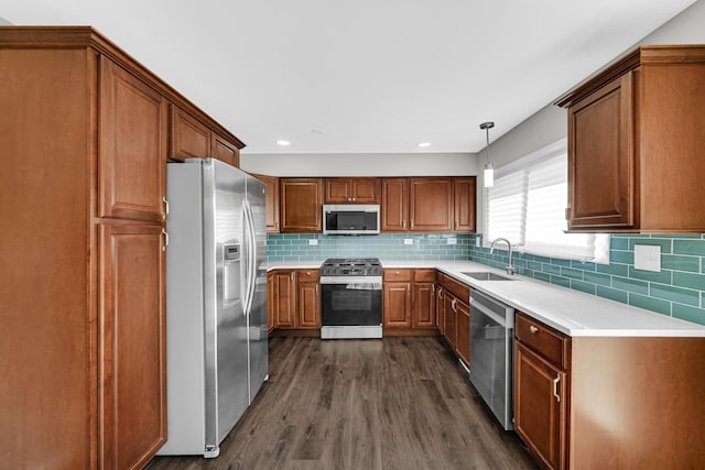 kitchen with a sink, decorative backsplash, brown cabinets, stainless steel appliances, and dark wood-style flooring