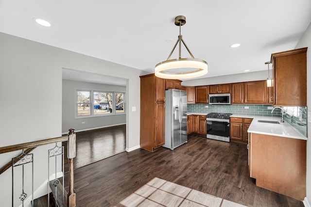 kitchen featuring a sink, tasteful backsplash, appliances with stainless steel finishes, brown cabinetry, and dark wood-style flooring