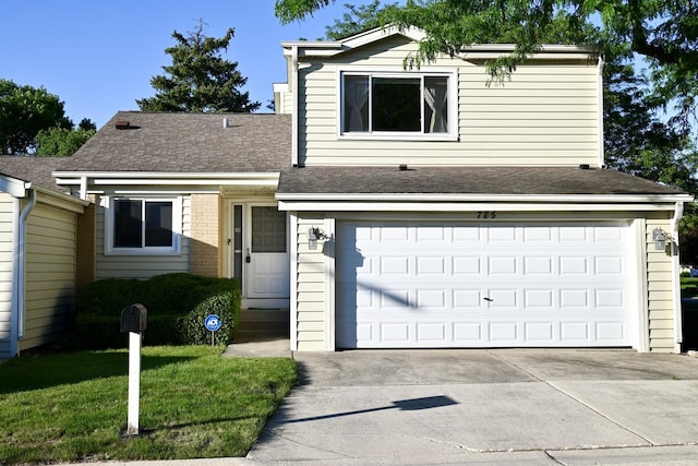 view of front facade with concrete driveway, an attached garage, a front lawn, and roof with shingles