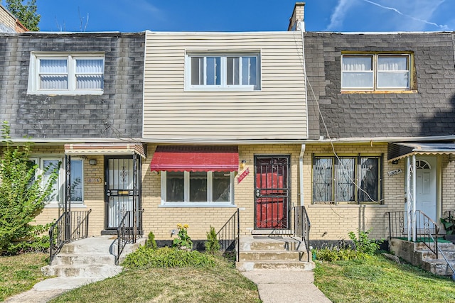 townhome / multi-family property with mansard roof, brick siding, and roof with shingles