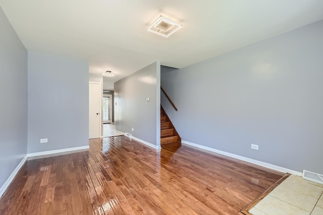 unfurnished room with visible vents, stairway, baseboards, and hardwood / wood-style floors