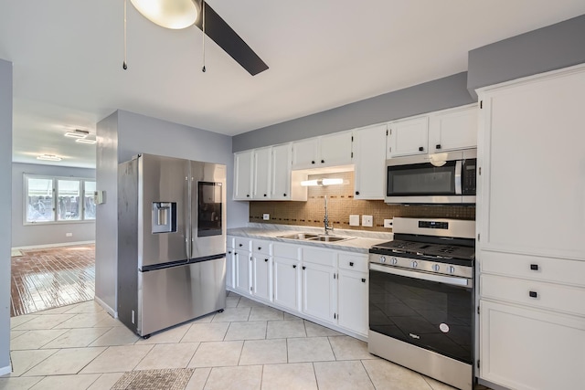 kitchen featuring light tile patterned floors, backsplash, appliances with stainless steel finishes, and a sink