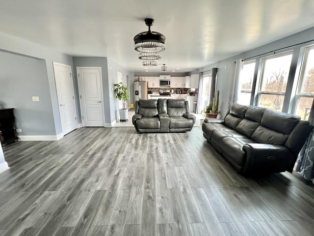 living room featuring baseboards, a notable chandelier, and wood finished floors