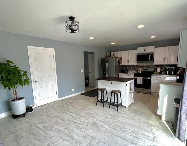 kitchen featuring a breakfast bar area, baseboards, a kitchen island, stainless steel appliances, and tasteful backsplash