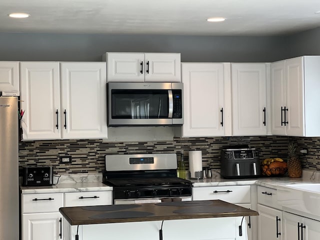 kitchen featuring wooden counters, backsplash, white cabinetry, and stainless steel appliances