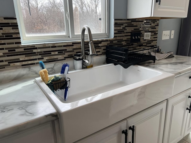 kitchen featuring white cabinetry, light countertops, backsplash, and a sink